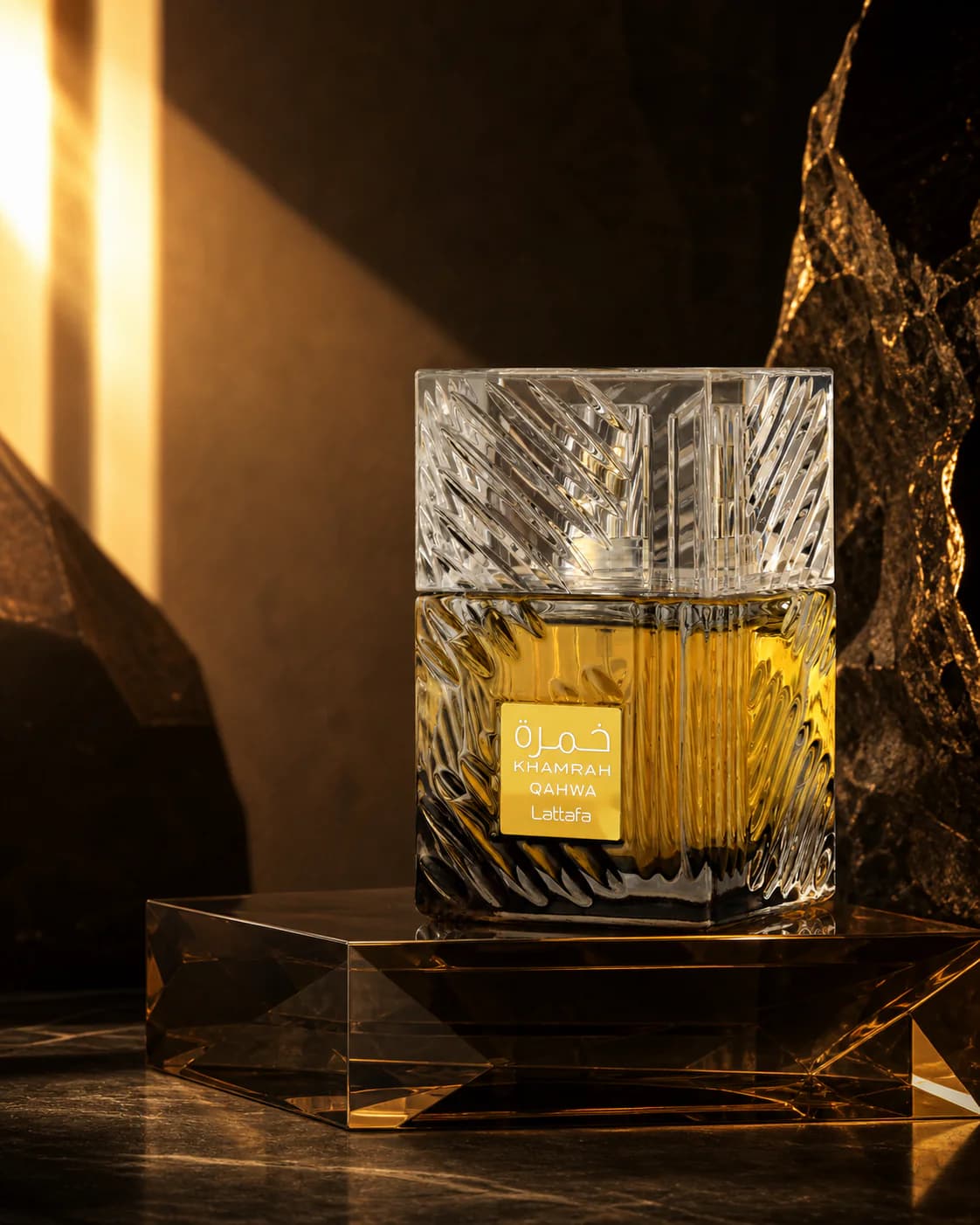 Lattafa Khamrah Qahwa crystal bottle glowing amber against dark stone